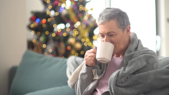 Close Up Portrait of Older Woman Drinking Tea on Couch Indoors