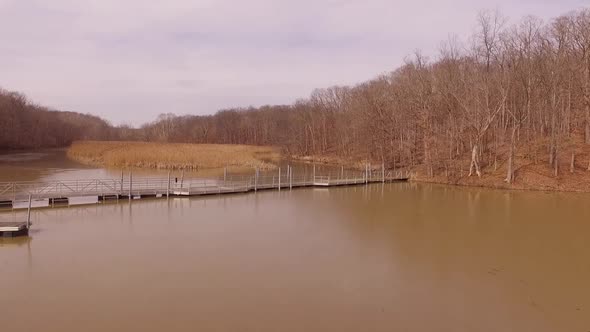 Aerial footage of a foot bridge crossing an icy lake during the winter at a state park