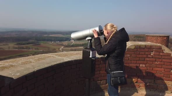 Attractive Female Traveller Using Tower Optical Viewer for Looking Around Valley Near the Old Castle