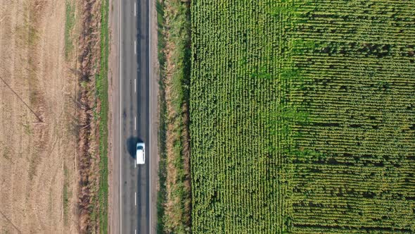 A Topdown Aerial View of a White Minibus Driving Along a Road on a Summer Morning