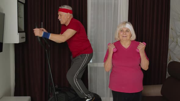 Senior Mature Grandfather and Grandmother Using Orbitrek Doing Weight Lifting Dumbbells Exercises