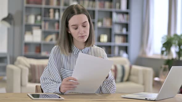 Young Woman Thinking and Writing on Paper in Office