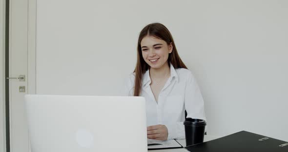 Young Office Girl Chatting with Smile on a Laptop at Work Place