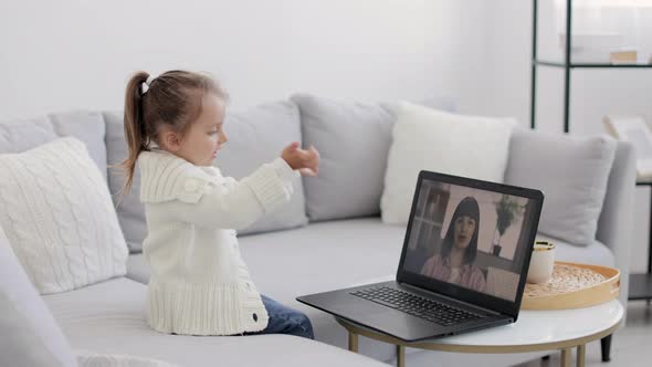 Back View of Young Girl Sitting and Relaxing on Sofa at Home and Talking on Video Call with Smiling