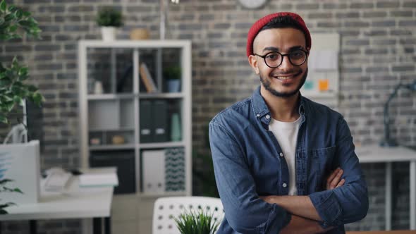 Portrait of Creative Young Man Standing in Office with Arms Crossed Smiling