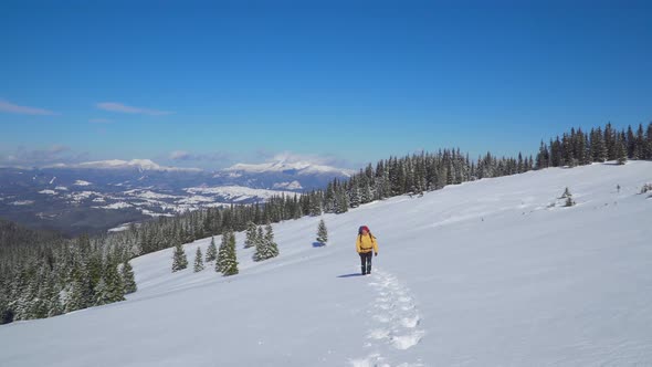 A Man with a Backpack Travels in the Mountains in Winter