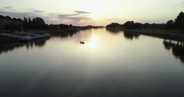 Aerial view of a small boat crossing Drava river at sunset, Osijek, Croatia.