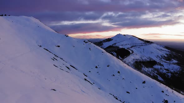 Aerial View of Snowcapped Mountain Slope in Winter During Sunrise or Sunset. Panorama of High Snow