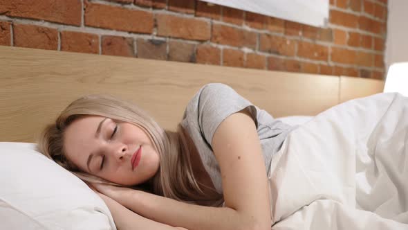 Young Woman Sleeping in Bed at Night on Side