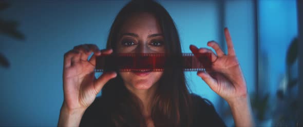 Woman looking at the film strip, then looking into camera