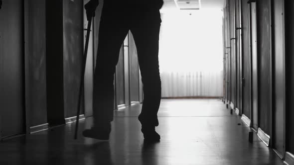 Man with Limp Walking along Corridor