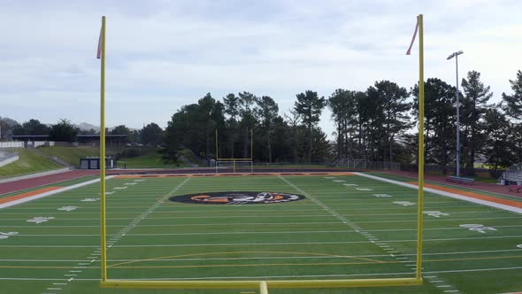 Aerial: Cougars High School football field and running track, flying forward.