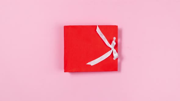 Heart-shaped white chocolate candies fly out of a gift red bag decorated with white ribbon.