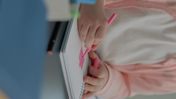 Vertical Video Close Up of Young Child Using Colorful Pencils on Notebook
