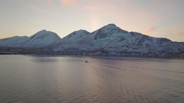 Flying above fjord on Kvaløya, Tromsø. Northern Norway. Following the wake of a fishing boat. 4K dr