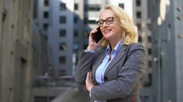 Cheerful Female Manager Talking on Phone Standing Outside, Client Communication