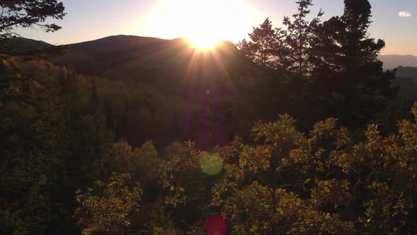 Aerial view of the sun setting on a beautiful mountainside in the fall.