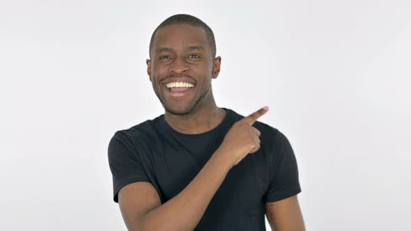 Young African Man Pointing on Side on White Background