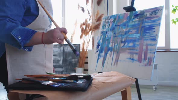 A Woman Paint Artist Taking a Brush and Drawing a Colorful Abstract Painting on a Canvas
