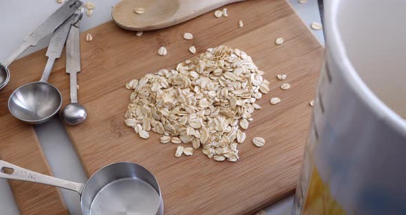 A pile of oats grain cereal animated into a heart shape with kitchen utensils for a healthy oatmeal