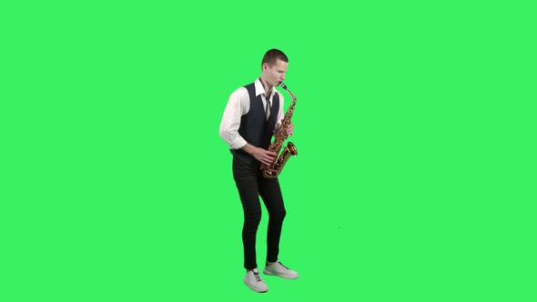 Portrait Stylish Young Guy Plays Melody at Saxophone on a Green Screen in the Studio. Saxophonist