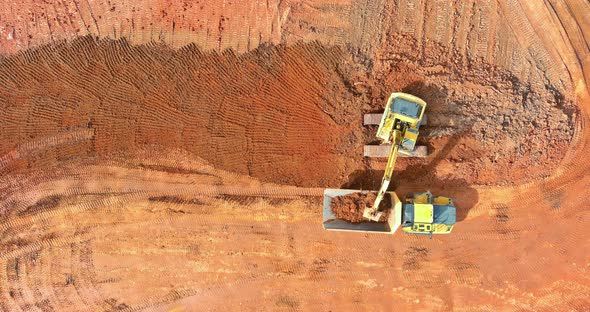 Aerial View of Excavator Loading Land Into Dump Trucks