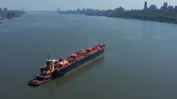 A drone view of a large red barge on the Hudson River in NY on a sunny day. The camera truck right a