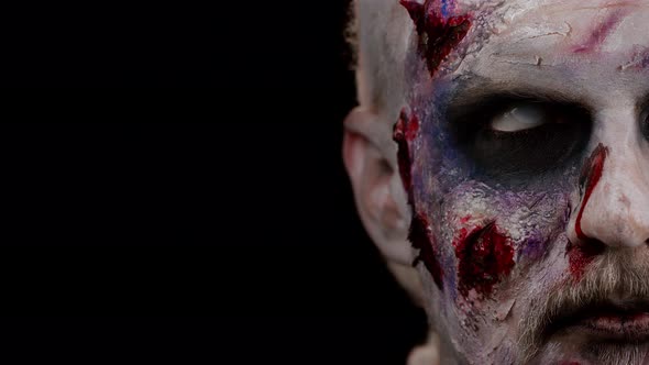 Closeup Face of Sinister Man with Horrible Scary Halloween Zombie Makeup Looking Creepy at Camera