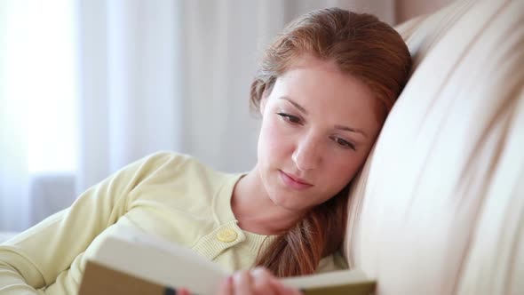 Young Woman Reading a Book on the Couch