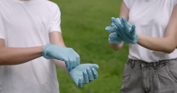 Young Volunteers Putting on Rubber Gloves Outdoors