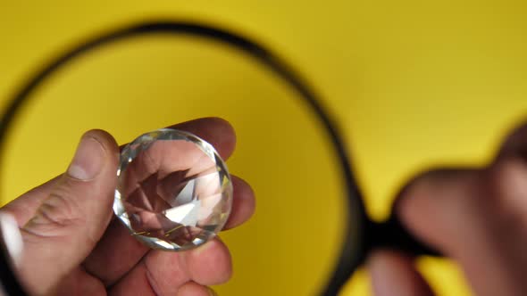 Jeweler Examines Diamond Under Magnifying Glass on yellow background,close up