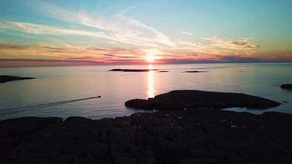 Drone flying over cliffs, towards sunset and motorboat