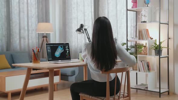 Close Up Of Asian Female Footwear Designer Stretching While Designing Shoe On A Laptop At Home