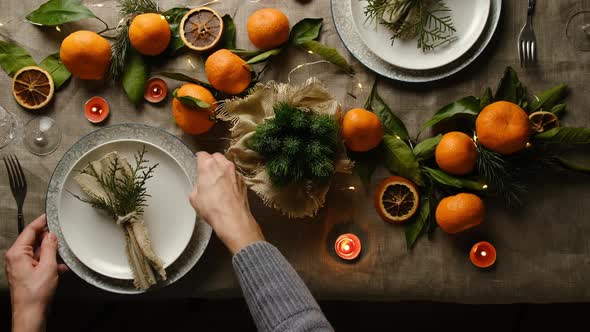 Woman Puts Plate with Napkin on Christmas Table