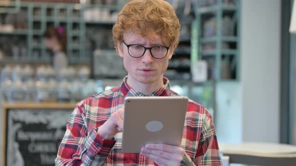 Excited Redhead Man Celebrating Success on Tablet 