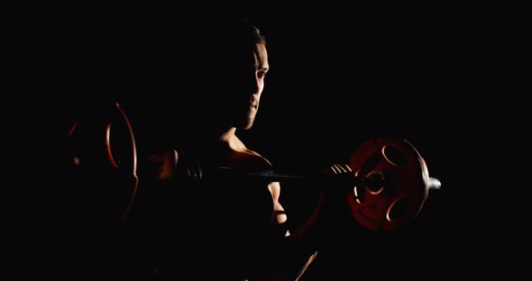 Athletic Man Doing Training In Gym Lifting A Barbell Black Background