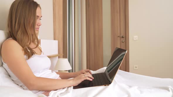 Woman Typing on Laptop in Bed.