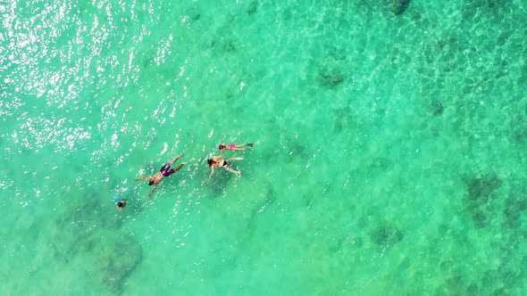 Young people swim on green turquoise calm shallow lagoon, watching beautiful rocks, corals and tropi