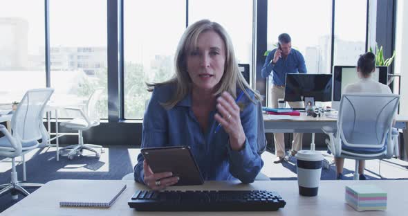 Woman using digital tablet and talking to camera