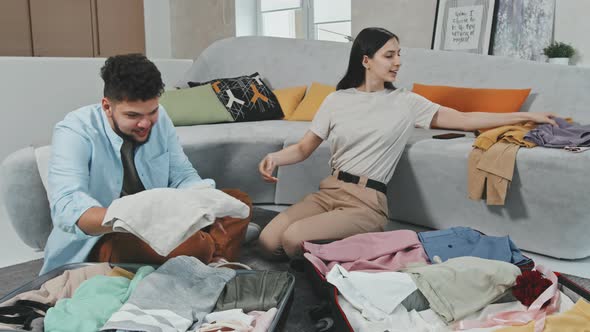 Young Couple Packing Suitcases Before Trip