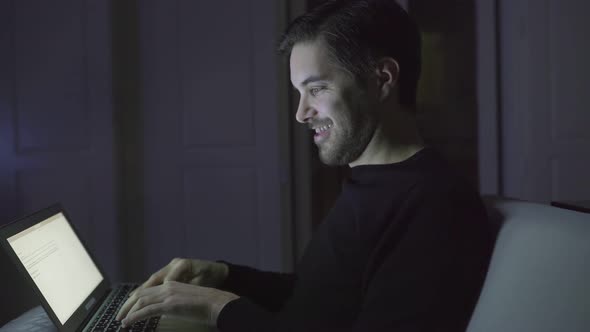 Smiling Young Man Typing on Laptop at Home