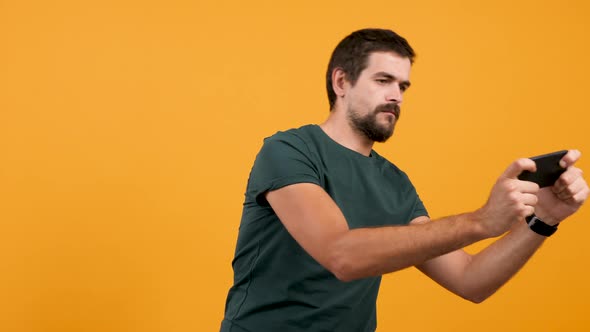 Young Attractive Man Playing a Video Game on His Smartphone