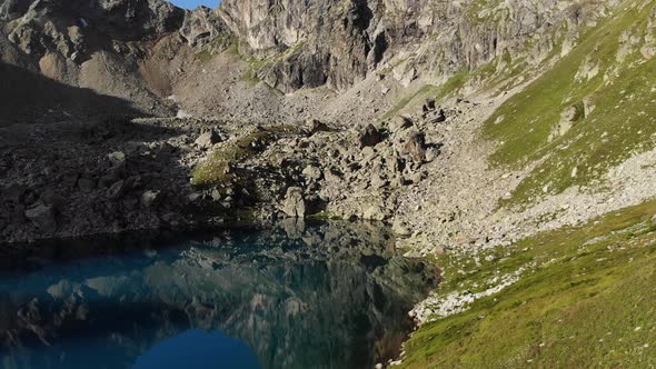 Aerial View of Flight Along the Shore of an Alpine Lake with Crystal Clear Drinking Water