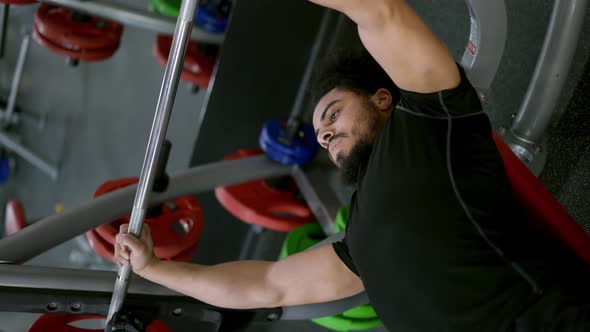 Man with Muscular Physique Spends Hard Workout Lifting Barbell in Gym