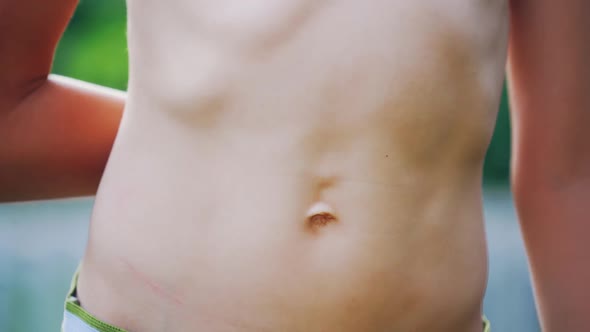 Close-up stomach of a boy. Young boy pulls his belly and shows ribs on his naked body.