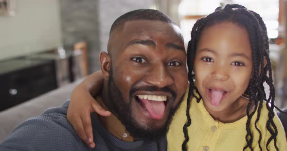 Portrait of happy african american daughter and father fooling around and taking selfie