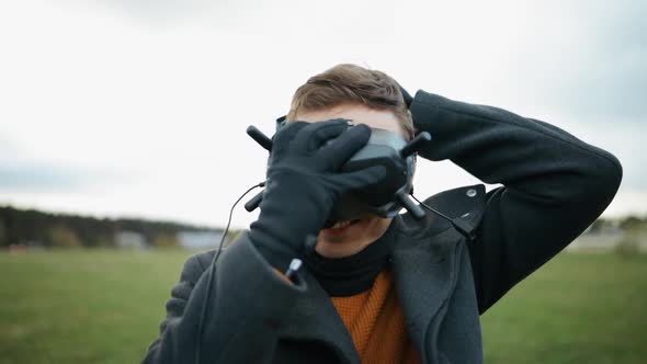 Smiling Man Puts on Black FPV Drone Goggles Outdoors