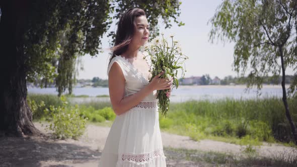 Portrait of Cute Young Girl with Long Brunette Hair Wearing a Long White Summer Fashion Dress