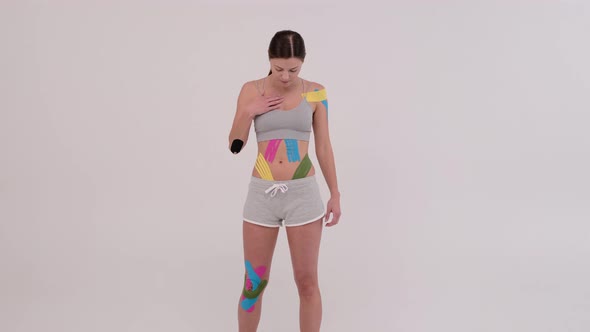 beautiful young female athlete posing colorful Kinesiotape on her body
