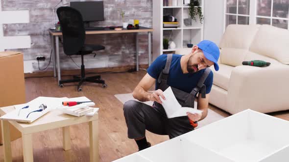 Caucasian Male Worker Looking Confused at Furniture Assembly Instructions